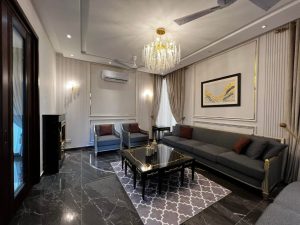 Luxurious living room with modern gray furniture, dark marble floor, and crystal chandelier. A beautifully designed residential space showcasing elegant seating, sophisticated wall treatments, and rich textures, ideal for contemporary living.